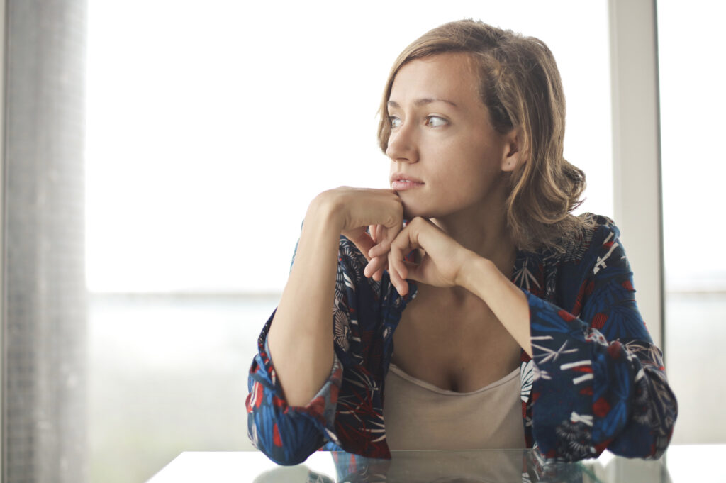 Allowing ourselves to grieve- attractive young woman with chin on hand sitting in contemplation at the kitchen table.